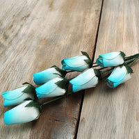 Wooden Closed Bud Rose #59 - White with Light Blue Tips arranged gracefully on a wooden table.